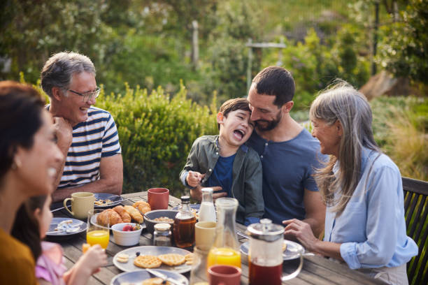 istock Little boy laughing during lunch outdoors with his multi-generation family 1813205546