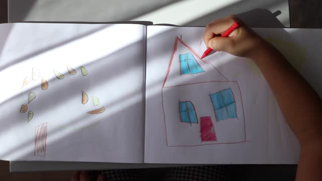 Top view of little girl drawing something in album. Home activity on holidays