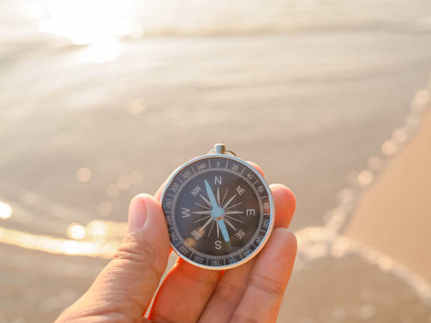 istock Close up hand holding compass with beach background 1813208038