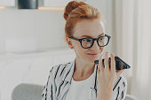 Smiling woman recording voice message on phone, communication concept