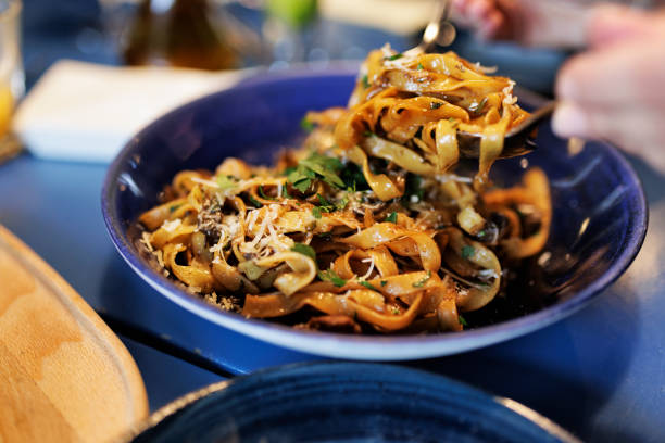Teenagers enjoying lunch in a restaurant. Closeup of Tagliatelle ai funghi porcini eaten by the teenage girl.Shot With Canon R5