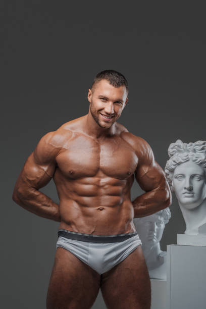istock Smiling Rugged Man with Perfect Muscular Torso and Greek Statues 1813253159