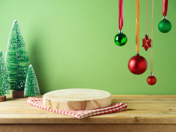 istock Empty log podium with tablecloth on wooden table over green wall and pine tree decoration background. Christmas mock up for design and product display. 1813256225