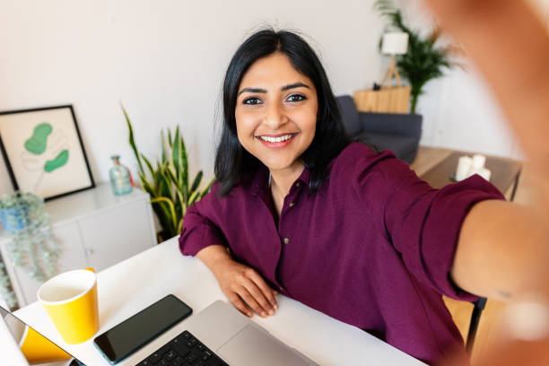 istock Smiling indian student taking self portrait while working on laptop at home 1813256565