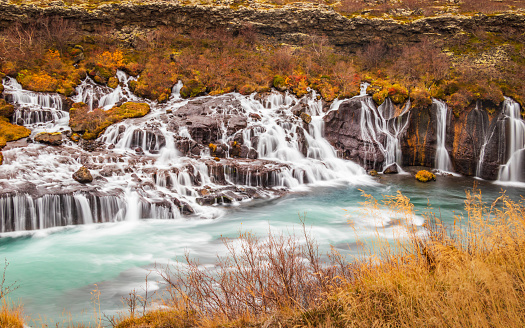 Hraunfossar ('Lava Falls') in Borgarfjörður, West Iceland, a series of beautiful waterfalls formed by rivulets streaming out of the Hallmundarhraun lava field. This majestic waterfall is so unique during the autumn.