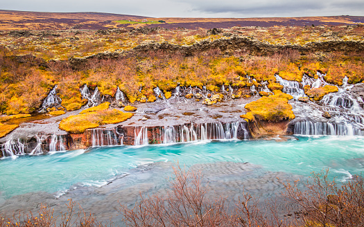 Hraunfossar ('Lava Falls') in Borgarfjörður, West Iceland, a series of beautiful waterfalls formed by rivulets streaming out of the Hallmundarhraun lava field. This majestic waterfall is so unique during the autumn.