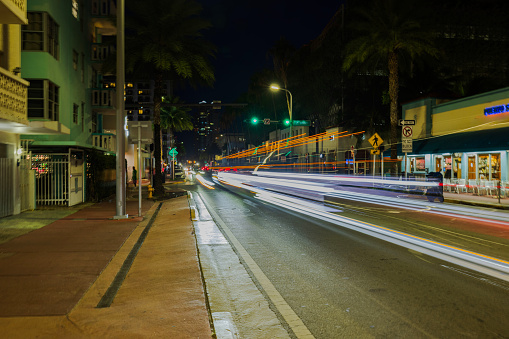 Nocturnal scene over Miami Beach with cityscape along Collins Avenue with blurred light tracers from passing cars.