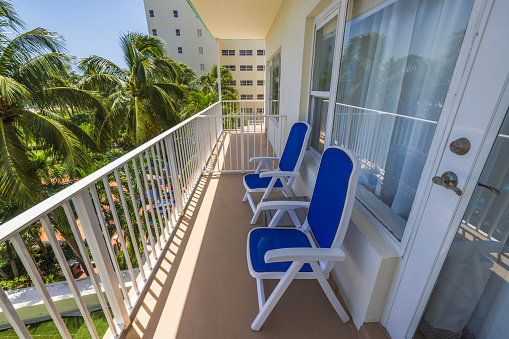 Hotel balcony offering sight with blue chairs and table for comfort of guests. Miami Beach. USA.