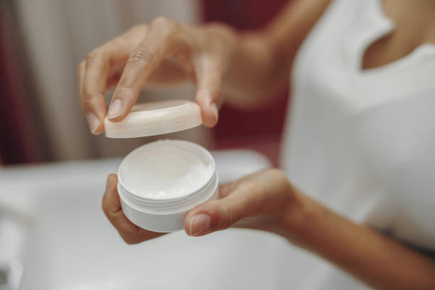 istock Close up of woman's hands holding moisturizer bottle while standing in bathroom 1813292151