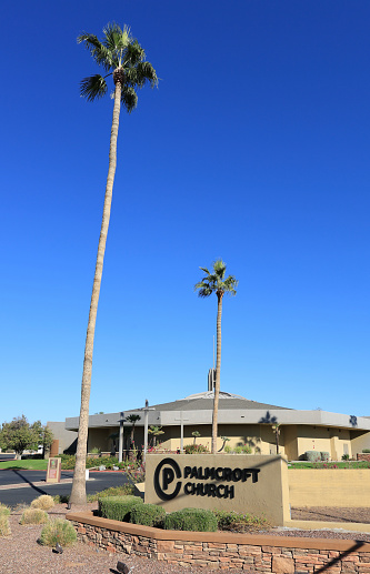 Phoenix, AZ - November 11, 2023:  Road sign and open entrance with tall palms leading to Palmcroft Church located along major city avenue in North-West Phoenix, Arizona