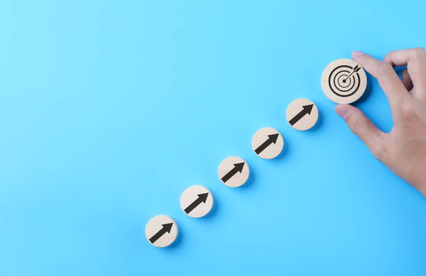 istock Business achievement goal and objective target concept. Businessman hand putting virtual business target and arrow which screen on round wooden block. Growth investing, Blue background, Copy space, 1813297445