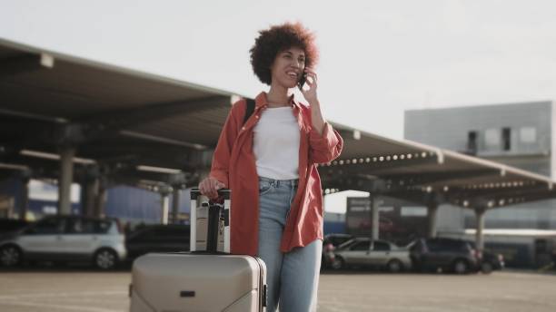 istock Happy woman with suitcase standing outdoors, talking on phone. 1813336767
