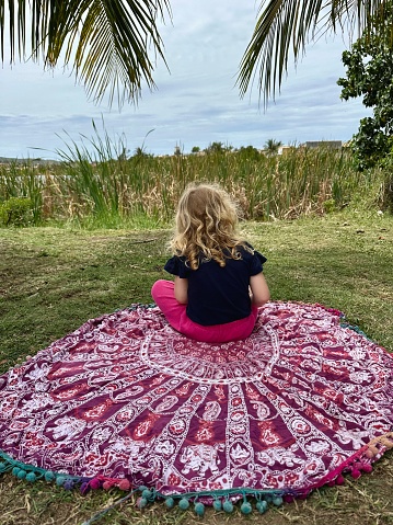 3-year-old sitting on circle shaped sarong close to lake in Buzios