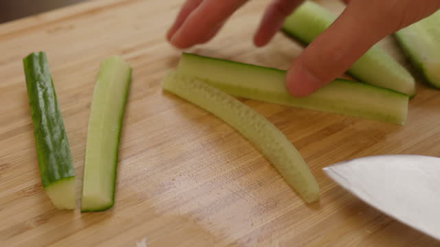 cutting cucumber on wooden chopping board