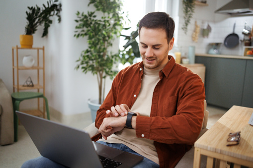 Man using smart watch while sitting in armchair at home