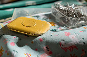Close-up of sewing supplies: tailors chalk, cotton fabric, pins, bobbins of thread, ...