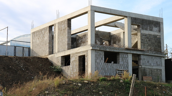 box of a two-story cottage under construction without a roof, a block building at the stage of erecting walls, construction of a residential building in a suburban area