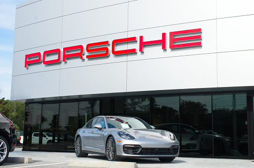 OCALA, FLORIDA USA - OCTOBER 22, 2023  Porsche dealership with red logo on front of building and  blue sky background