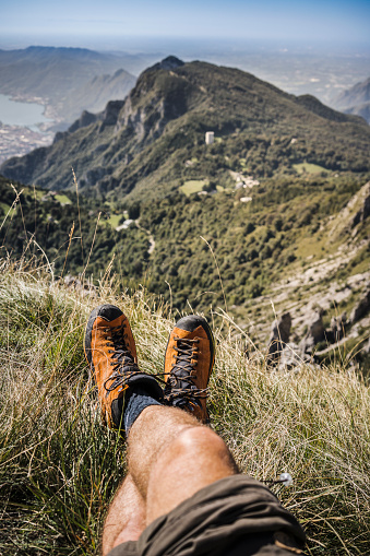 man resting on high mountain meadow, legs crossed pov view