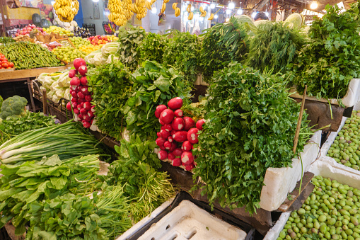 Fresh autumn vegetables at the farmer's market including purple radishes, delicata and butternut squash, fennel and bags of lettuce