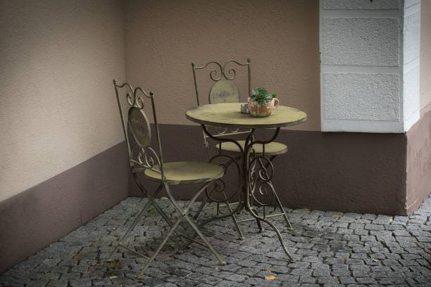 istock Patio with an old metallic table and two chairs on a cobblestone street 1813506351