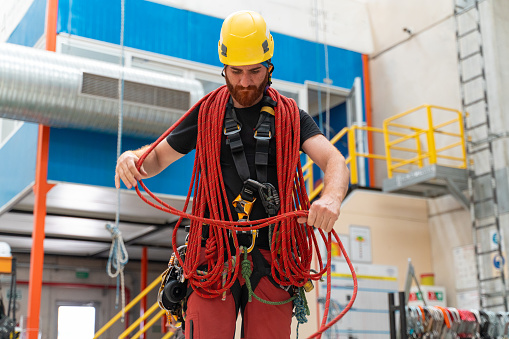 Male engineer in protective suit checking climbing rope