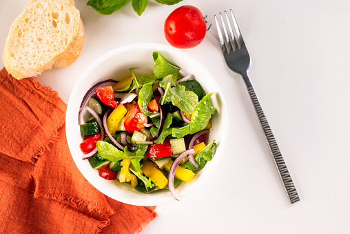 Fresh salad with tomato, cucumber, bel pepper in white bowl, ready for serving