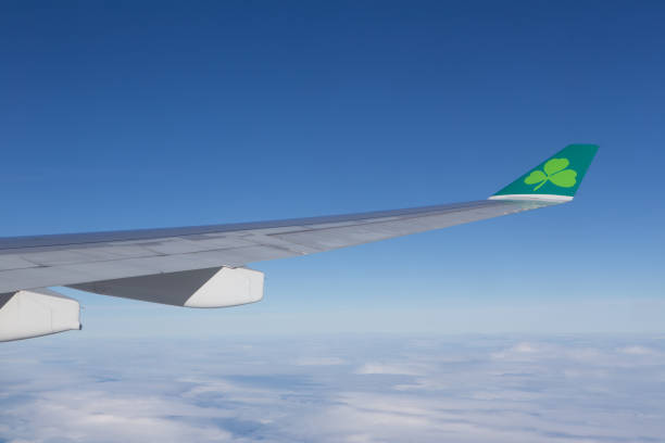 View from an Airplane window of an Aer Lingus wing with Aer Lingus clover logo on tip of wing with clouds in the background