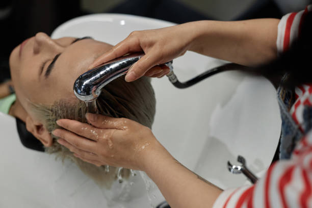friseur wäscht sorgfältig die haare eines männlichen kunden im waschbecken eines schönheitssalons - lightener stock-fotos und bilder