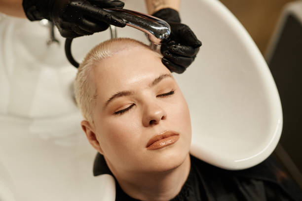 mujer joven con corte de pelo disfrutando del lavado de pelo en el salón de belleza - lightener fotografías e imágenes de stock