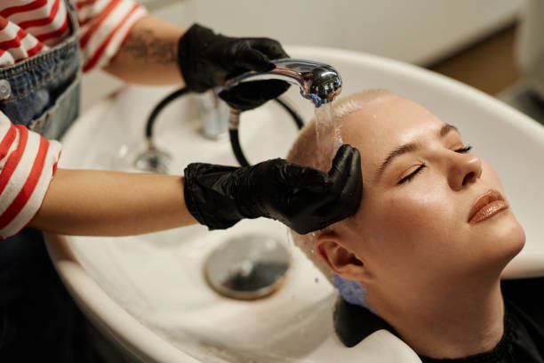 junge frau genießt haarwäsche im waschbecken des schönheitssalons - lightener stock-fotos und bilder