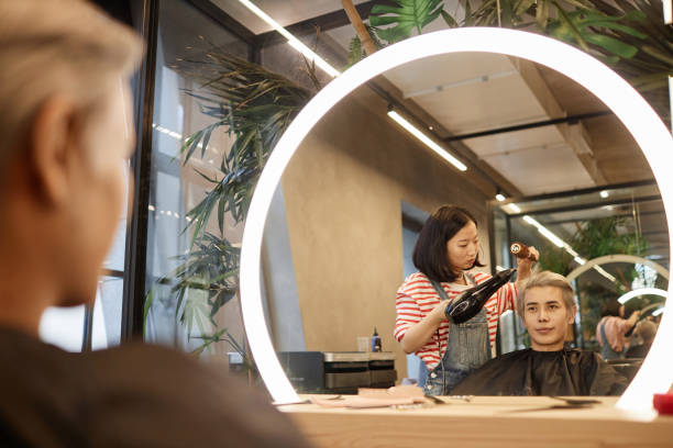 reflejo del espejo del peluquero que seca y peina el cabello en el salón de belleza - lightener fotografías e imágenes de stock