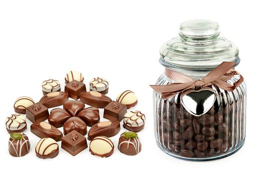 Set of chocolate candies and chocolate dragee in a glass jar isolated on a white background. Free space for text. Collage.
