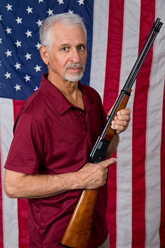 USA Second Amendment constitutional Right to Bear Arms. Senior man American flag background.