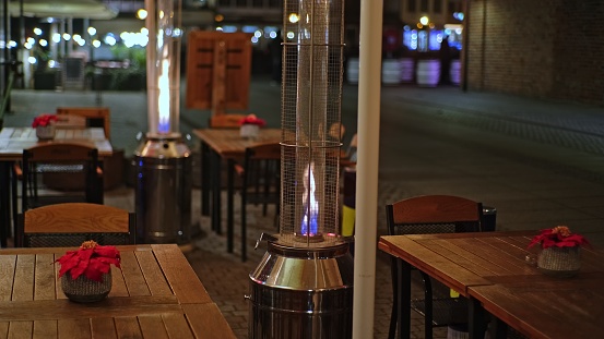 Outdoor Patio Garden Gas Heater Burning with Blue and Yellow Flame on Cold Evening Low Angle
