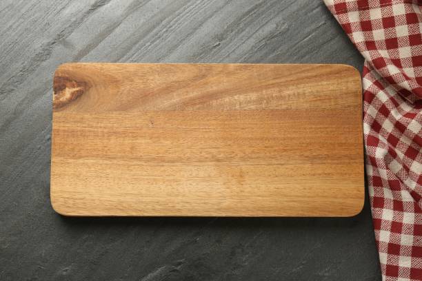 istock Wooden cutting board and kitchen towel on dark grey table, top view 1813640464