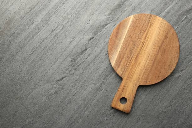 istock One wooden cutting board on dark grey table, top view. Space for text 1813641040
