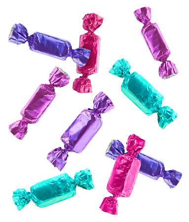 Tasty candies in bright wrappers falling on white background