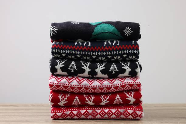istock Stack of different Christmas sweaters on wooden table against light background 1813649596