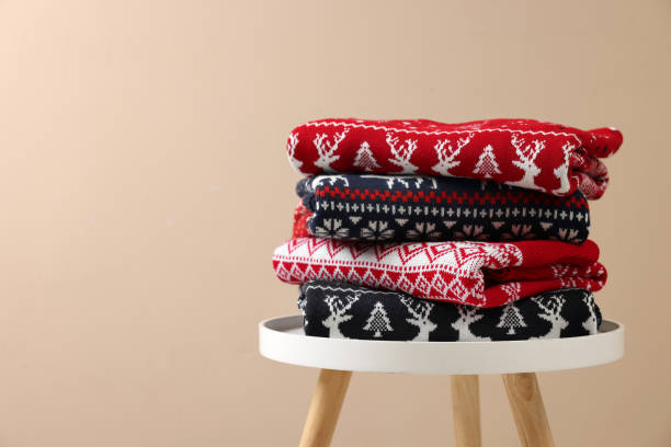 istock Stack of different Christmas sweaters on white table against beige background. Space for text 1813649997