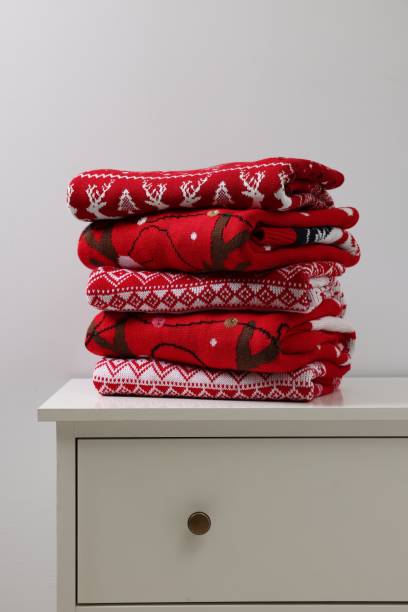 istock Different folded Christmas sweaters on chest of drawers against light background 1813651303