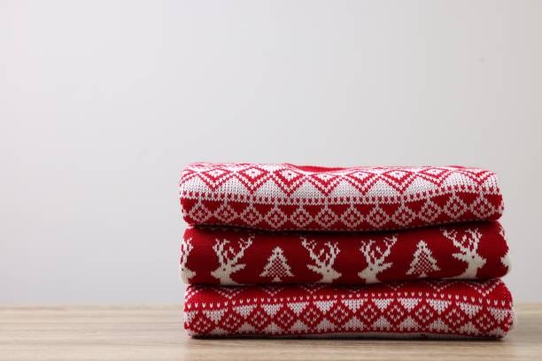 istock Stack of different Christmas sweaters on wooden table against light background. Space for text 1813651308