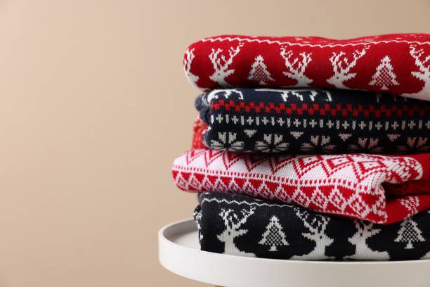 istock Stack of different Christmas sweaters on white table against beige background, closeup. Space for text 1813651316