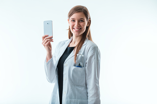 Presenting her smartphone, the doctor might be illustrating how mobile applications are changing the landscape of patient engagement and care management