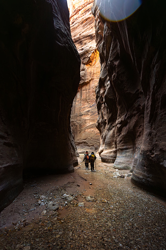 Two women walking in the river using walking sticks and carrying backpacks in the Narrows at Zion national park Utah