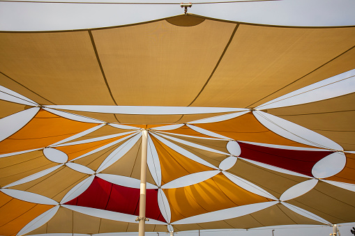 Colourfully Sun Tent on Blue Sky. Yellow, Orange and Red Shade Sails Pattern.