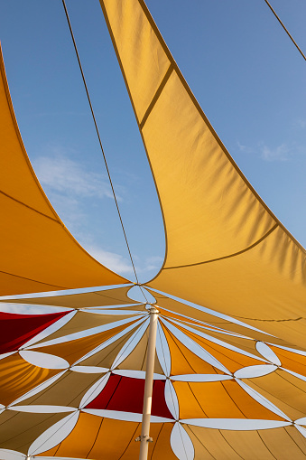 Colourfully Sun Tent on Blue Sky. Yellow, Orange and Red Shade Sails Pattern.