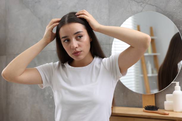 istock Woman examining her hair and scalp at home. Dandruff problem 1813697750