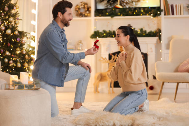 istock Man with engagement ring making proposal to his girlfriend at home on Christmas 1813698751