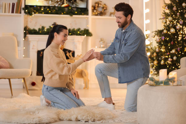 istock Man with engagement ring making proposal to his girlfriend at home on Christmas 1813698762